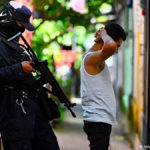 Un agente de policía interroga a un joven durante un operativo de seguridad contra las pandillas en Soyapango, al este de San Salvador. (16.08.2022)