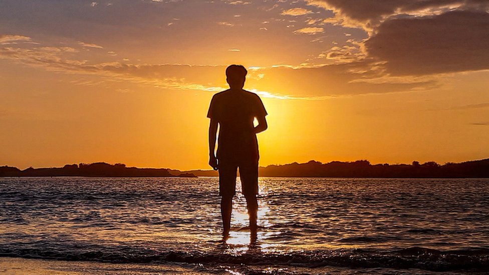 La silueta de un hombre observando el sol poniente