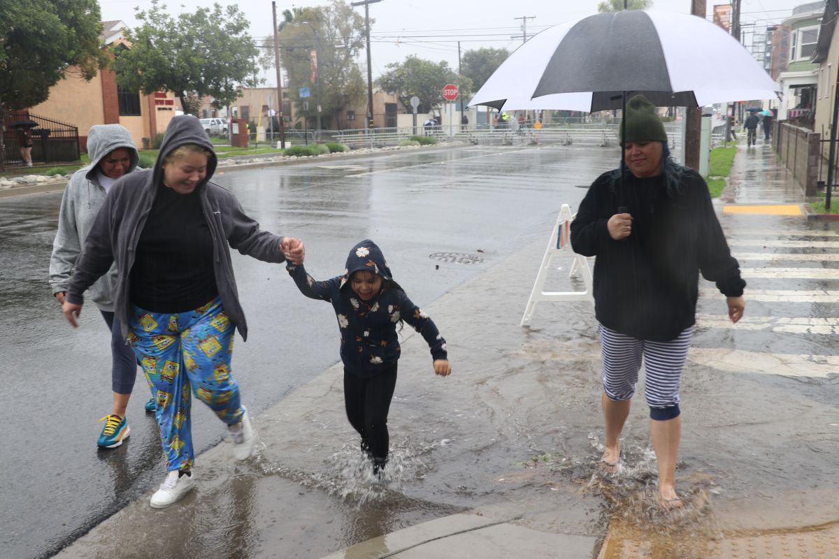 Angélica Barba, Lissette Martínez, Cassandra Williams y la pequeña Leilani cruzan una calle en medio del agua anegada. 