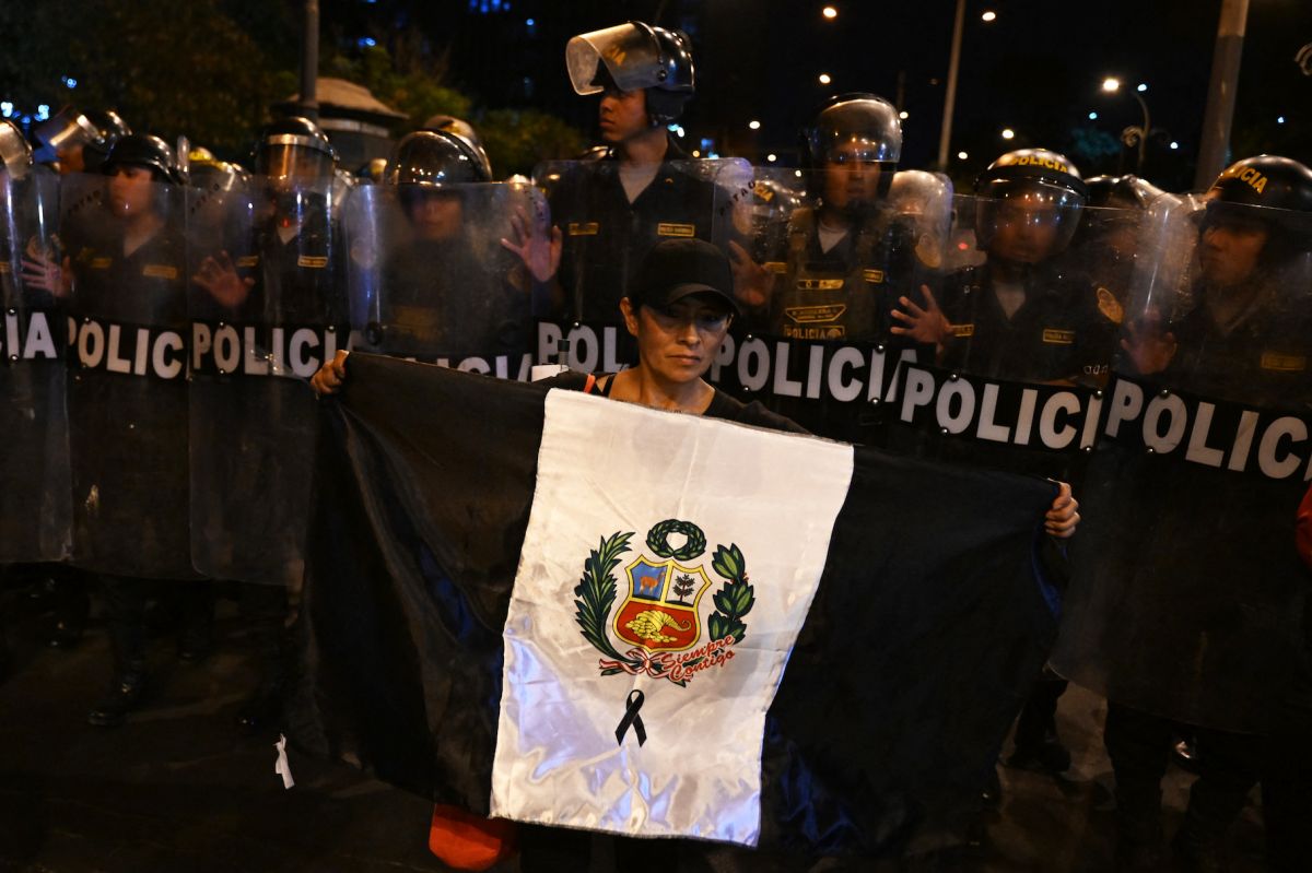 Una mujer ondea una bandera peruana pintada de negro por las víctimas de protestas pasadas durante una protesta contra el gobierno de la presidenta peruana Dina Boluarte en Lima