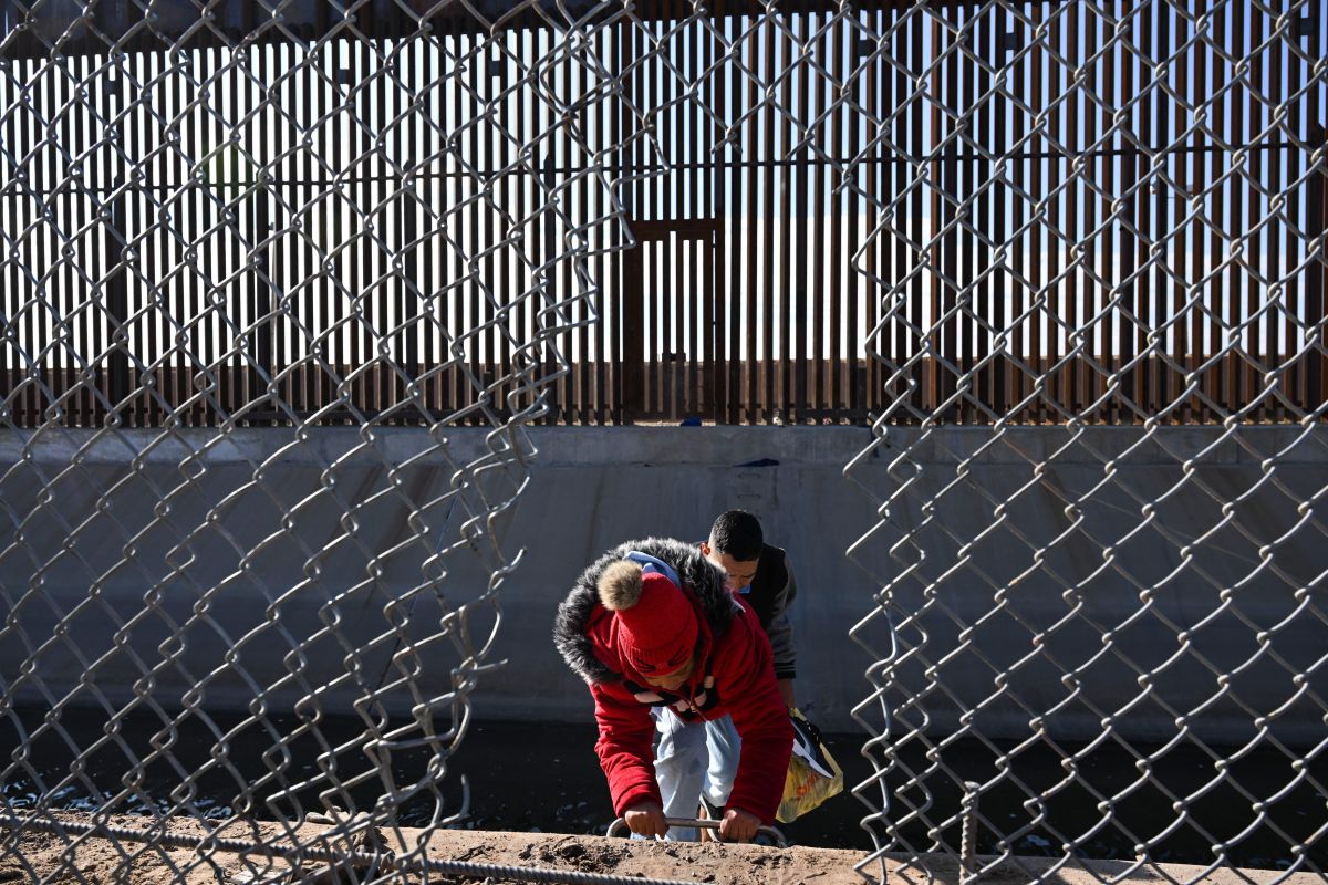 Una familia de migrantes cruza un agujero en el muro fronterizo en El Paso, Texas, el 19 de diciembre de 2022.