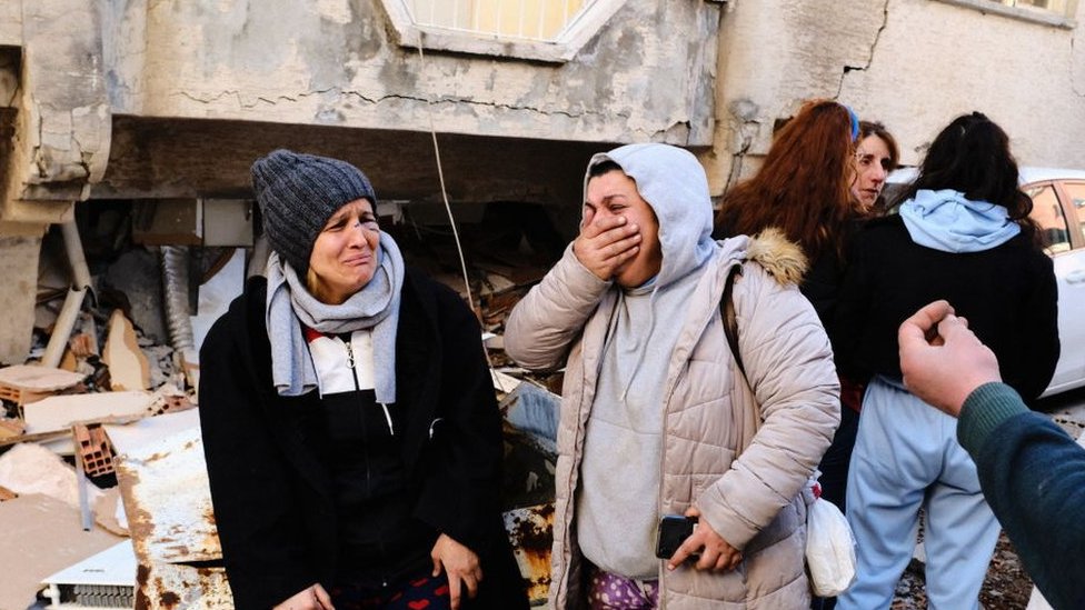 Residentes de Hatay, Turquía, lloran delante de eidicio derruido por el terremoto