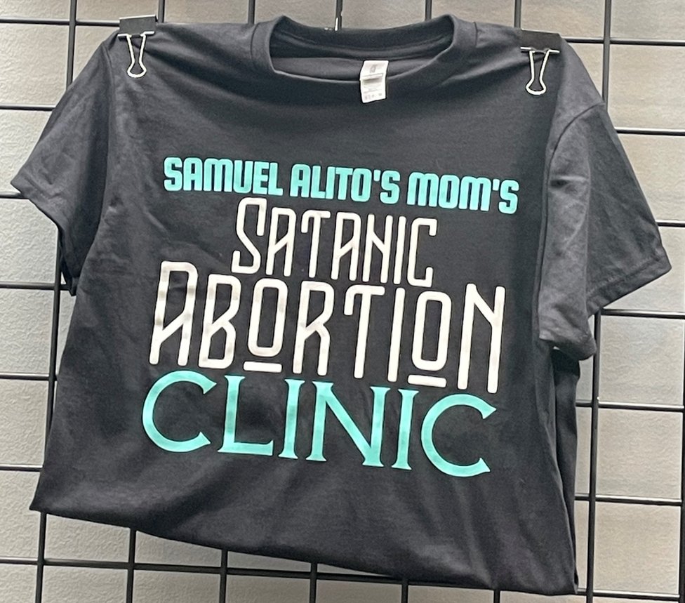 Una camiseta a la venta en SatanCon dice: "Clínica de aborto satánico de la madre de Samuel Alito", el nombre de la clínica de telesalud que el Satanic Temple abrió en Nuevo México.